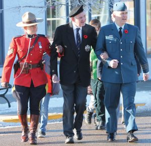 RCMP Sgt. Laura Akitt and Col. Stephane Guevremont assisted 94-year-old veteran Stan Edwards on the march from the cenotaph on Second Avenue to the community hall. 