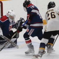 Fort Macleod Mavericks goalie Owen Archibald turns aside this scoring chance by Anthony Boyce of the Havre Ice Hawks, with Kylan Blackwater (16) coming in to clear the rebound.
