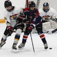 Pryce Schneider of the Fort Macleod Mavericks battles for the puck in front of Havre Ice Hawks goalie Sean Nagel.