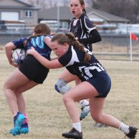 Minnie Toone of the F.P. Walshe Flyers tackles a Matthew Halton Hawk with Aby McClung coming in to support.