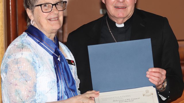 Holy Cross Catholic Women’s League president Evelyn McTrowe accepts a certificate recognizing the group’s 100th anniversary from Bishop William McGratton.